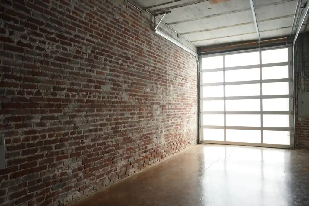 A spacious room with an exposed brick wall, polished concrete floor, and a large glass garage door letting in bright natural light—expertly crafted by a general contractor Contra Costa & Alameda County, CA.