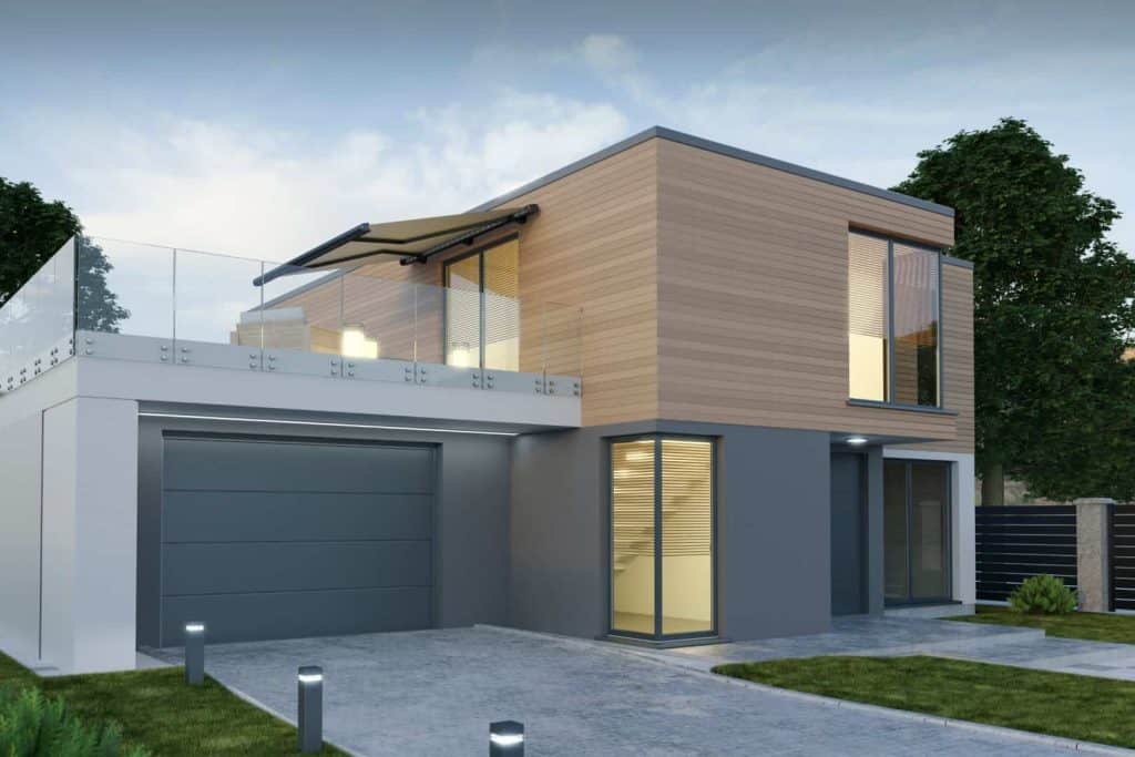 Modern two-story house with a flat roof, large windows, glass balcony, and wood paneling. Expertly built with General Contractor Services Bay Area, CA. Features driveway, garage, lush greenery, and illuminated front path.